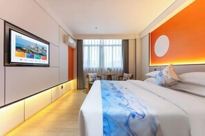 Ett hotellrum med en säng, en tv som är monterad på väggen, ett litet bord och en stol.