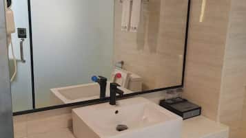 A bathroom with a white sink, a mirror, and a glass shower enclosure.
