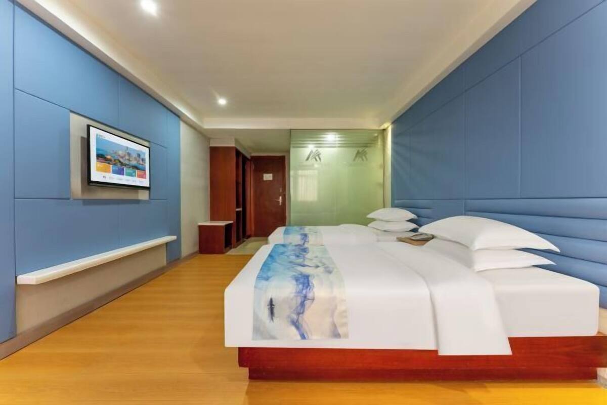 Ein Hotelzimmer mit einem großen Bett, einem an der Wand befestigten Fernseher und Holzboden.