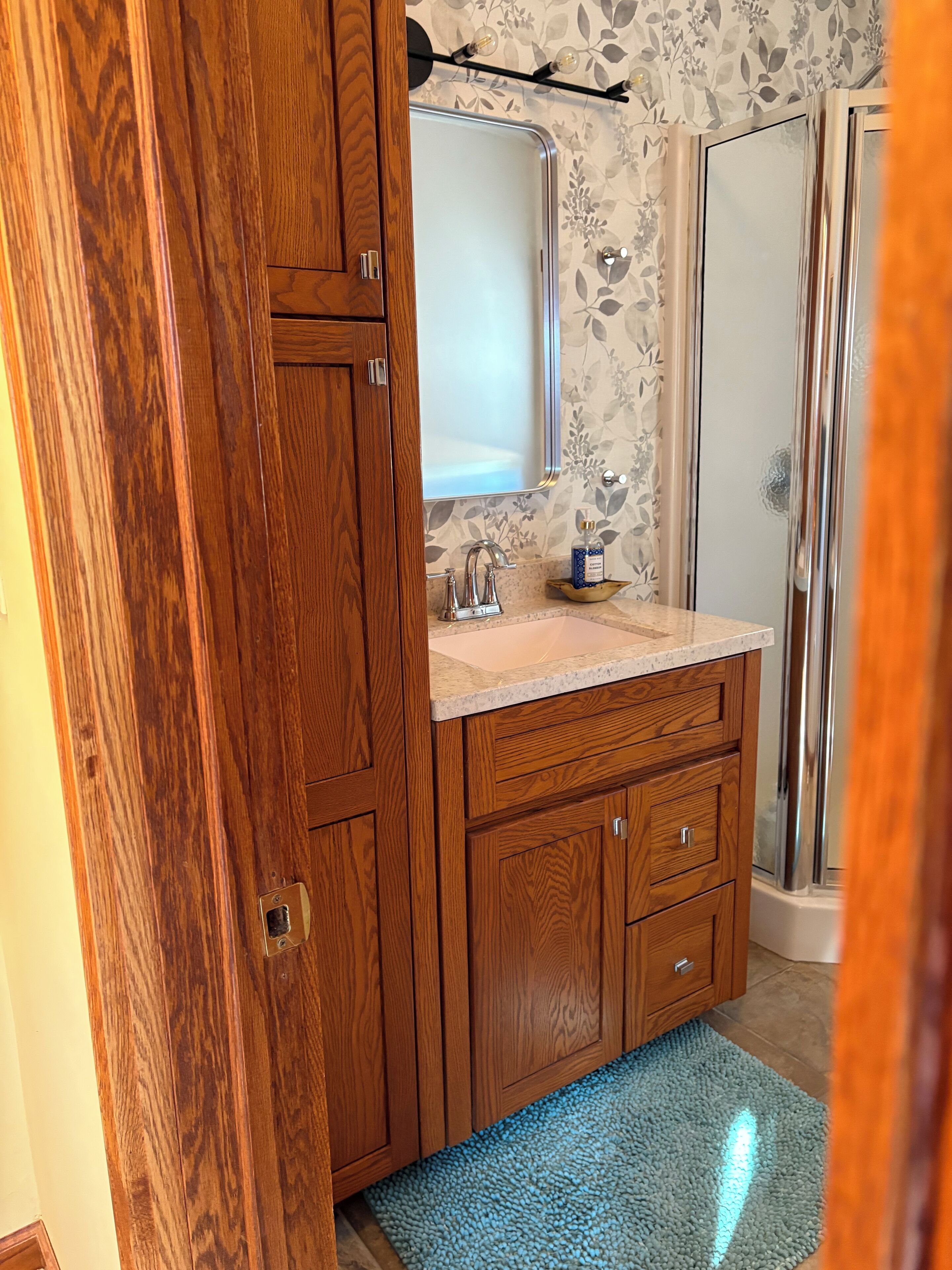 Un baño con muebles de madera, lavamanos de mármol y cabina de ducha de vidrio.