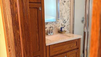 A bathroom with wooden cabinetry, a marble sink, and a glass shower enclosure.