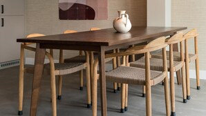 A dining area with a wooden table and chairs, a hanging light fixture, and a decorative vase. - 4 Person Apartment in the City Center (The Hague)