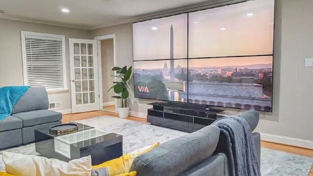 A living room with a large window, a sofa, a coffee table, and a TV.