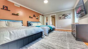 Quarto com duas camas, uma TV e uma cômoda.