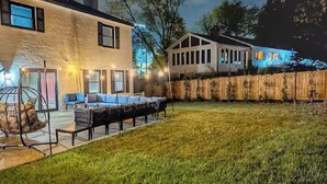 A backyard with a patio area, a swing set, and a wooden fence.