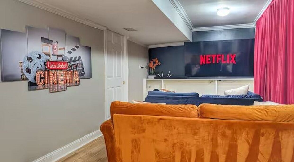 Una sala de estar con un sofá, una pared con un letrero de cine y un letrero de Netflix.