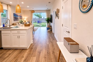 Una cocina moderna con una isla central, suelo de madera e iluminación colgante.