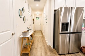 A kitchen with a stainless steel refrigerator, wooden flooring, and a white door. - Family Retreat - Arcade, Fire Pit, Game Room, King Bed - 2 mi Downtown! (St. Augustine)