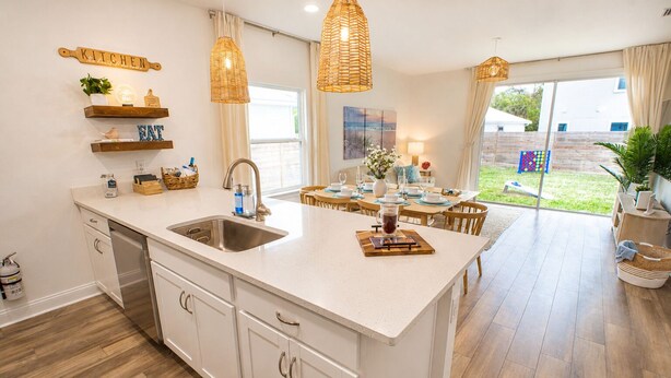 A modern kitchen with a large island, white cabinetry, and a dining area with a view. - Family Retreat - Arcade, Fire Pit, Game Room, King Bed - 2 mi Downtown! (St. Augustine)