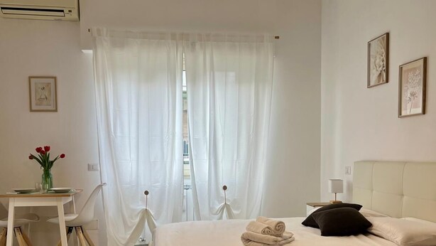 A bedroom with a bed, bedside table, and a hanging light fixture.