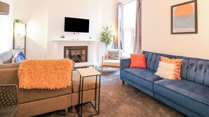 Una sala de estar con chimenea, un sofá, un televisor y una mesa de centro.