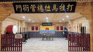 A traditional wooden room with a sign in the center, a table with chairs, and a red fence. - Dasheng Chinese Inn (Wusong Island Scenic Area) (Jilin City)
