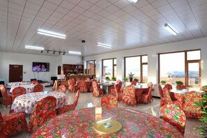 A conference room with round tables, chairs, a television, and large windows.