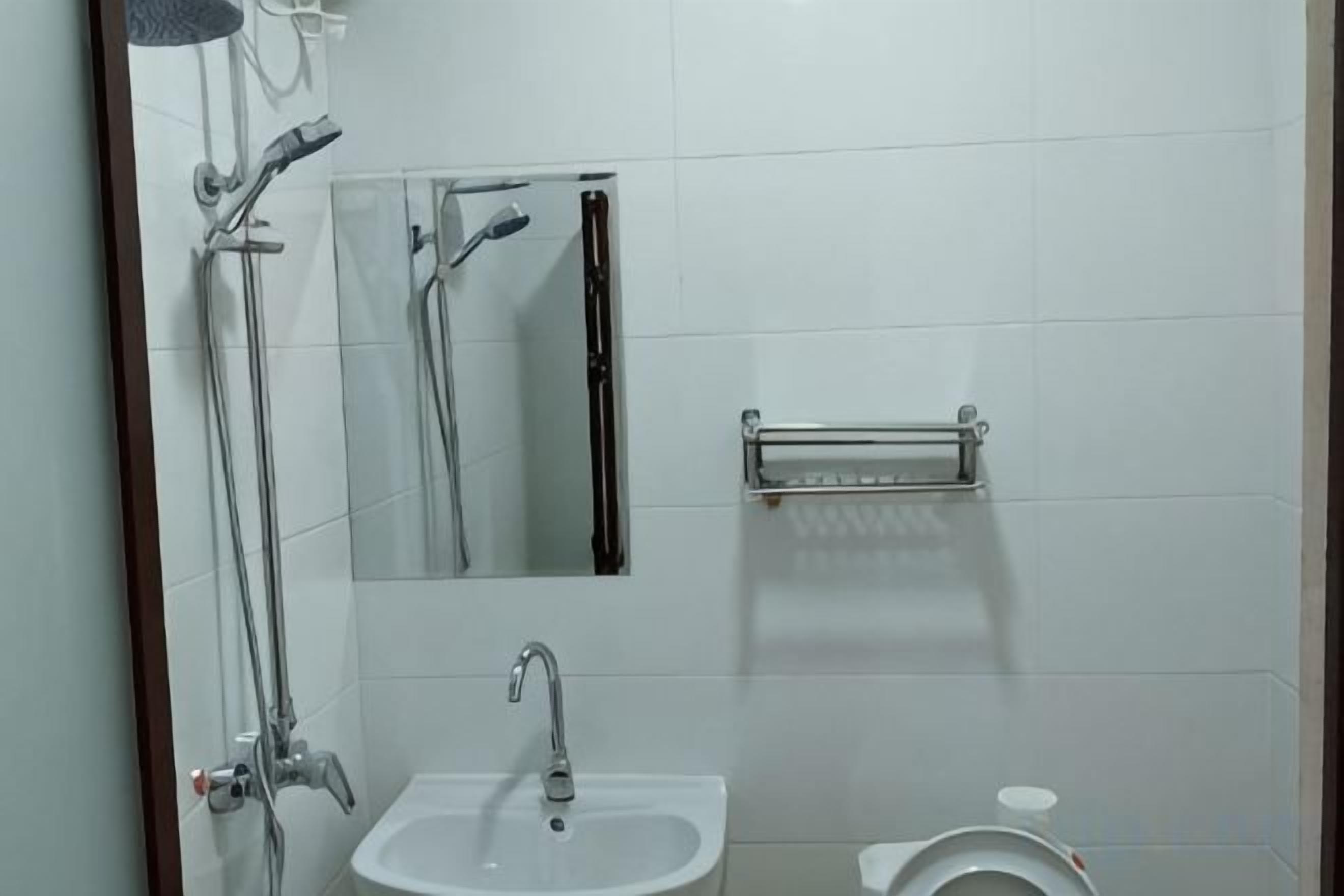 Un baño con lavamanos, espejo, ducha e inodoro.