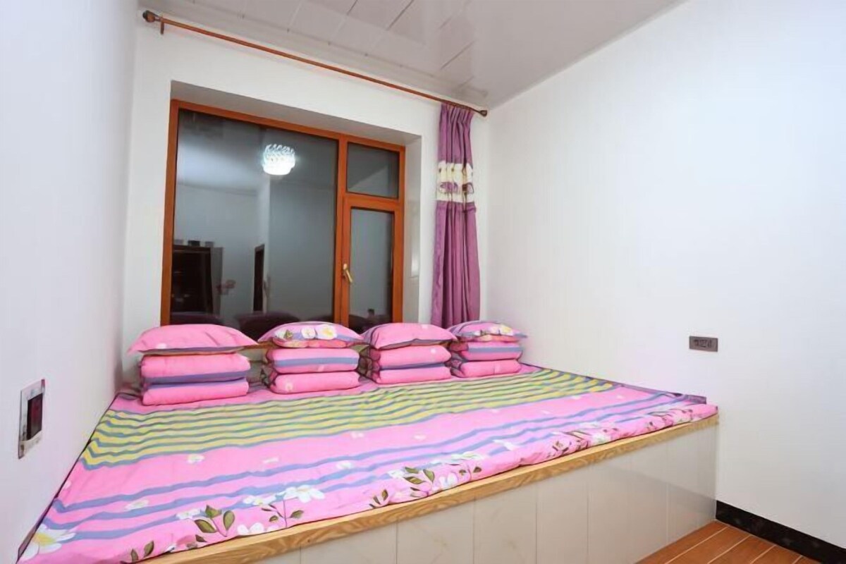 Un dormitorio con cama, ventana y cortinas.