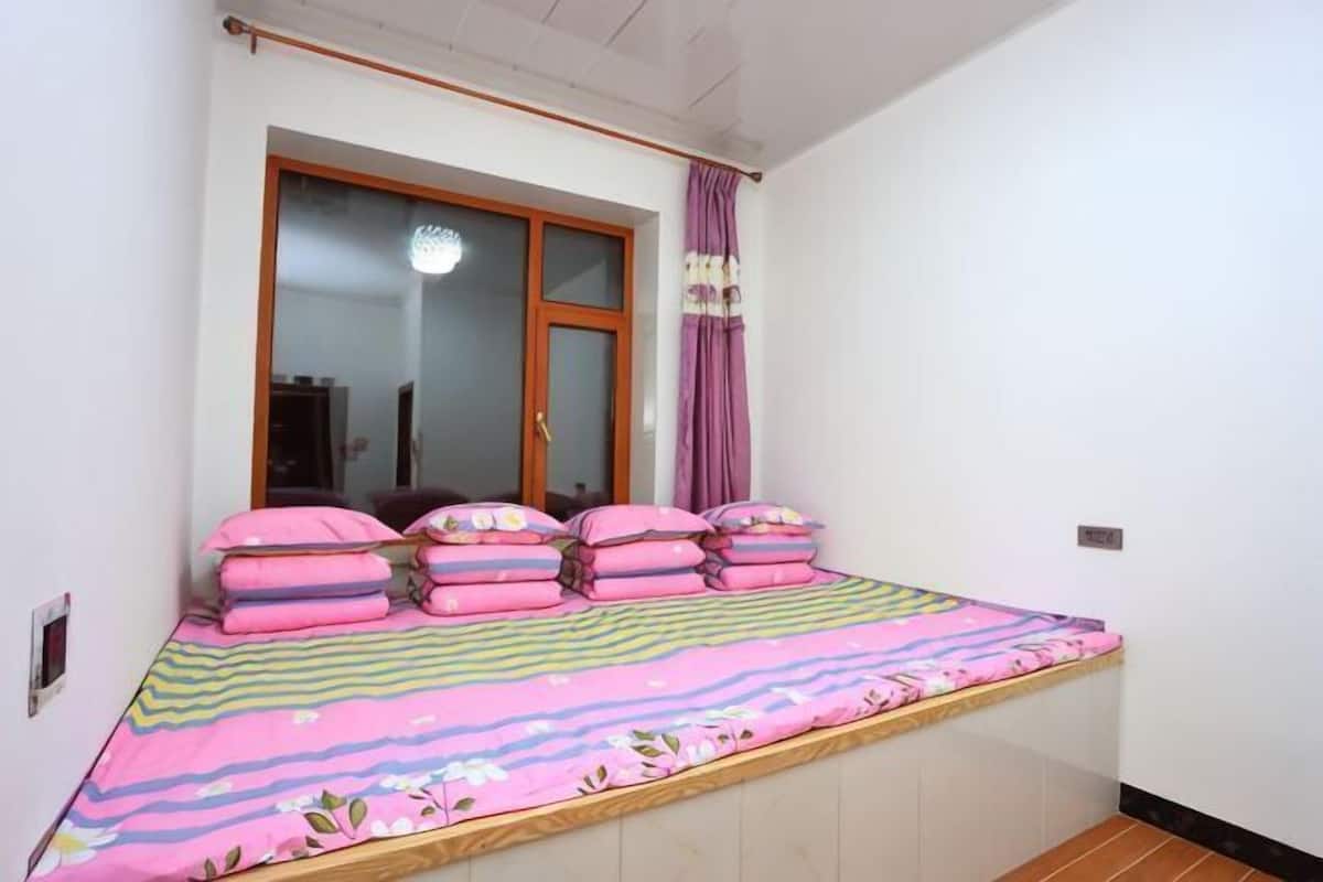 A bedroom with a bed, window, and curtains.