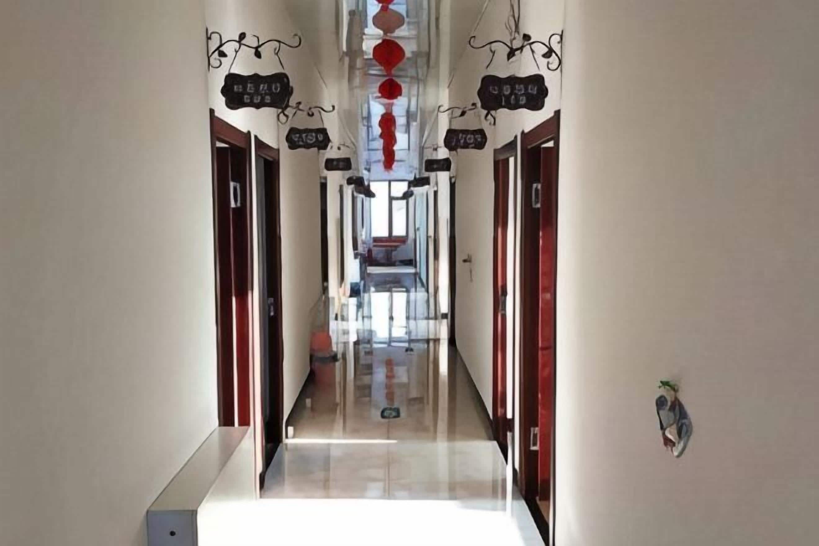 A hotel hallway with doors on either side, a central corridor, and hanging signs.