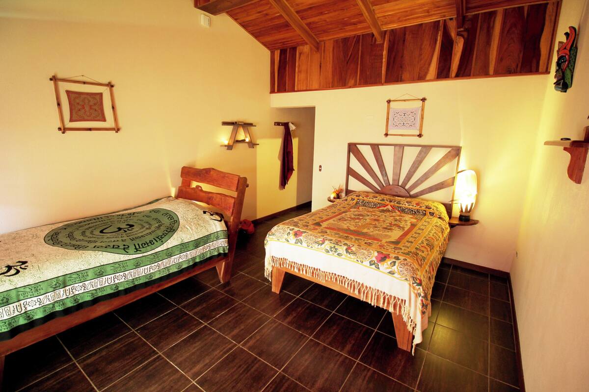 Una habitació amb dos llits de fusta, sostre de fusta i terra d'rajola.