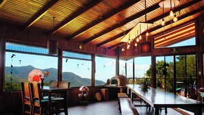 Un restaurante con interior de madera, ventanas amplias y vistas a montañas.