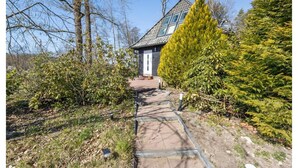 Eine Holzhütte mit Glasdach, umgeben von dichtem Grün und Bäumen.
