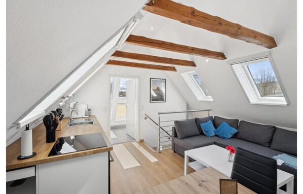 Un loft moderno con cocina, comedor y sala de estar. Cuenta con vigas de madera a la vista, tragaluces y vistas al exterior.