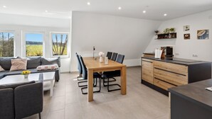 Eine moderne Küche mit Holztisch und -stühlen, einem eingebauten Backofen und einer Arbeitsplatte mit Kaffeemaschine.