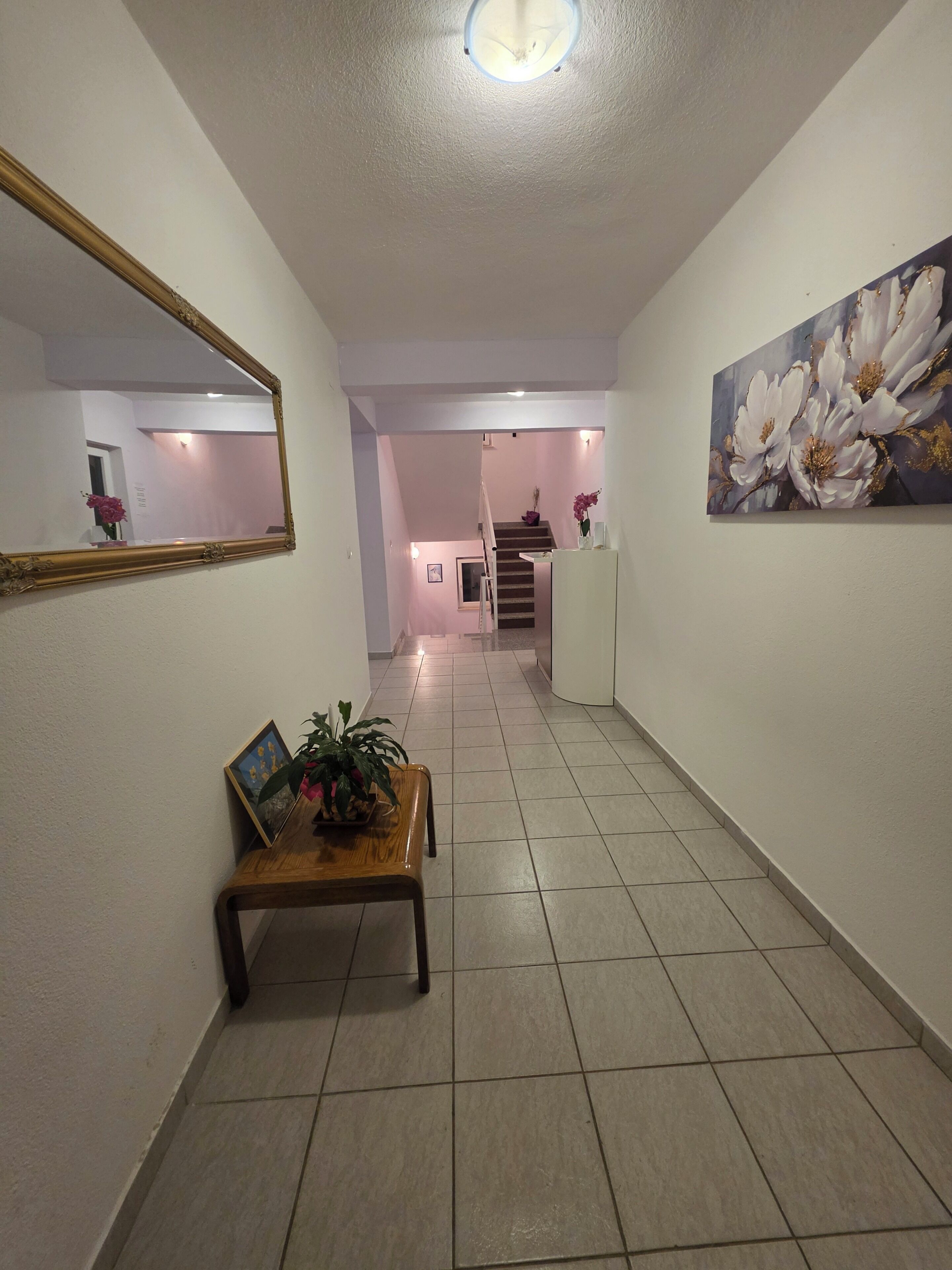 Un couloir avec un banc en bois, un miroir et un tableau accroché au mur.