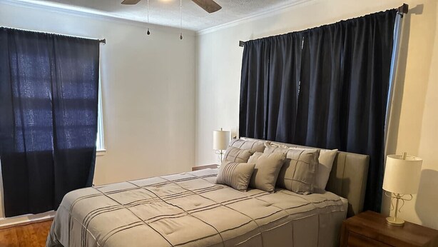 A bedroom with a bed, nightstands, a lamp, and curtains. - Suite A at Blue Sky Terrace (Columbus)