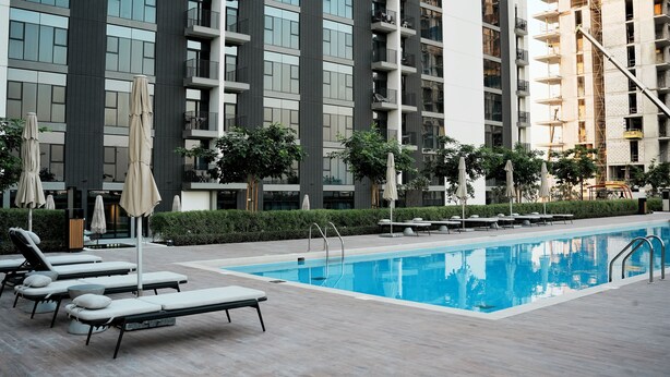 Een modern hotel met een zwembad, ligbedden en terras.
