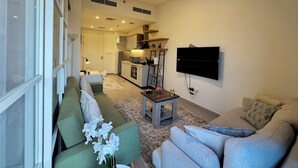 Een moderne woonkamer met een bank, een salontafel en een aan de muur bevestigde televisie.