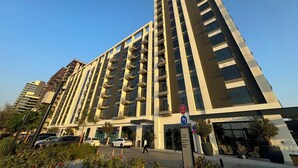 Een modern hoog gebouw met meerdere balkons en een begane grond ingang.