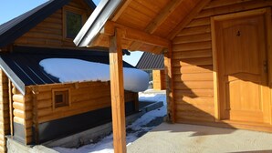 Een houten blokhut met een sneeuwbedekte dak, een houten deur en een raam.