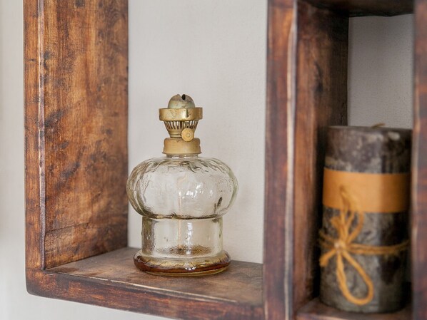 A wooden shelf with a glass bottle and a wrapped cylindrical object.