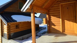 A wooden cabin with a snow-covered roof and a wooden door.