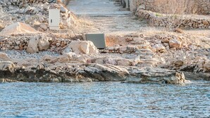 Un bâtiment situé sur la côte, doté d’une façade en pierre, d’un toit recouvert de tuiles rouges et offrant une vue sur la mer.