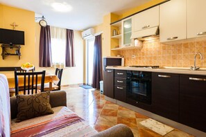 Cozy living space with a kitchenette, sofa, dining table, and TV.