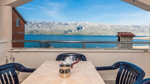Une terrasse avec une table et des chaises, donnant sur un lac avec des montagnes en arrière-plan.