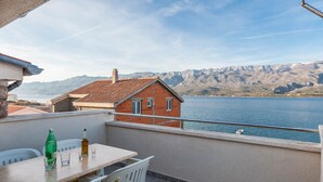 Ein Balkon mit Tisch und Stühlen mit Blick auf einen See und Berge.