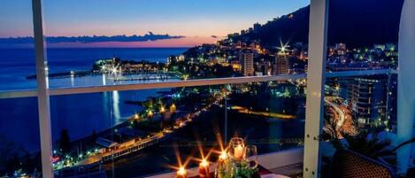 A table set for two with a view of a cityscape at dusk.