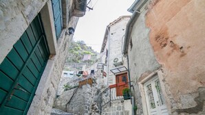 A narrow stone street with a steep incline, stone buildings with wooden shutters, and a small staircase leading up. - Cozy Stay in Kotor’s Old Town - Studio Apartment (Kotor)