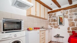 Une cuisine compacte équipée d’un lave-linge, d’un four à micro-ondes et d’un petit coin repas avec une table et des chaises.