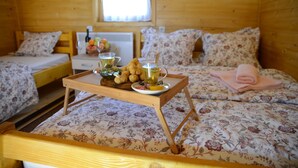 A wooden cabin room with a bed, a small table with breakfast items, and a window. - Cozy Berane Stay in Ski Area with On-Site Restaurant - Lux Cottage (Berane)