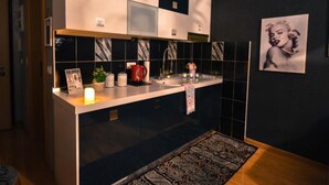 A modern kitchen with black and white tiles, a stainless steel sink, and a framed picture on the wall.