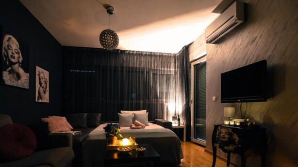 A modern bedroom with a bed, bedside table, and a TV mounted on the wall.