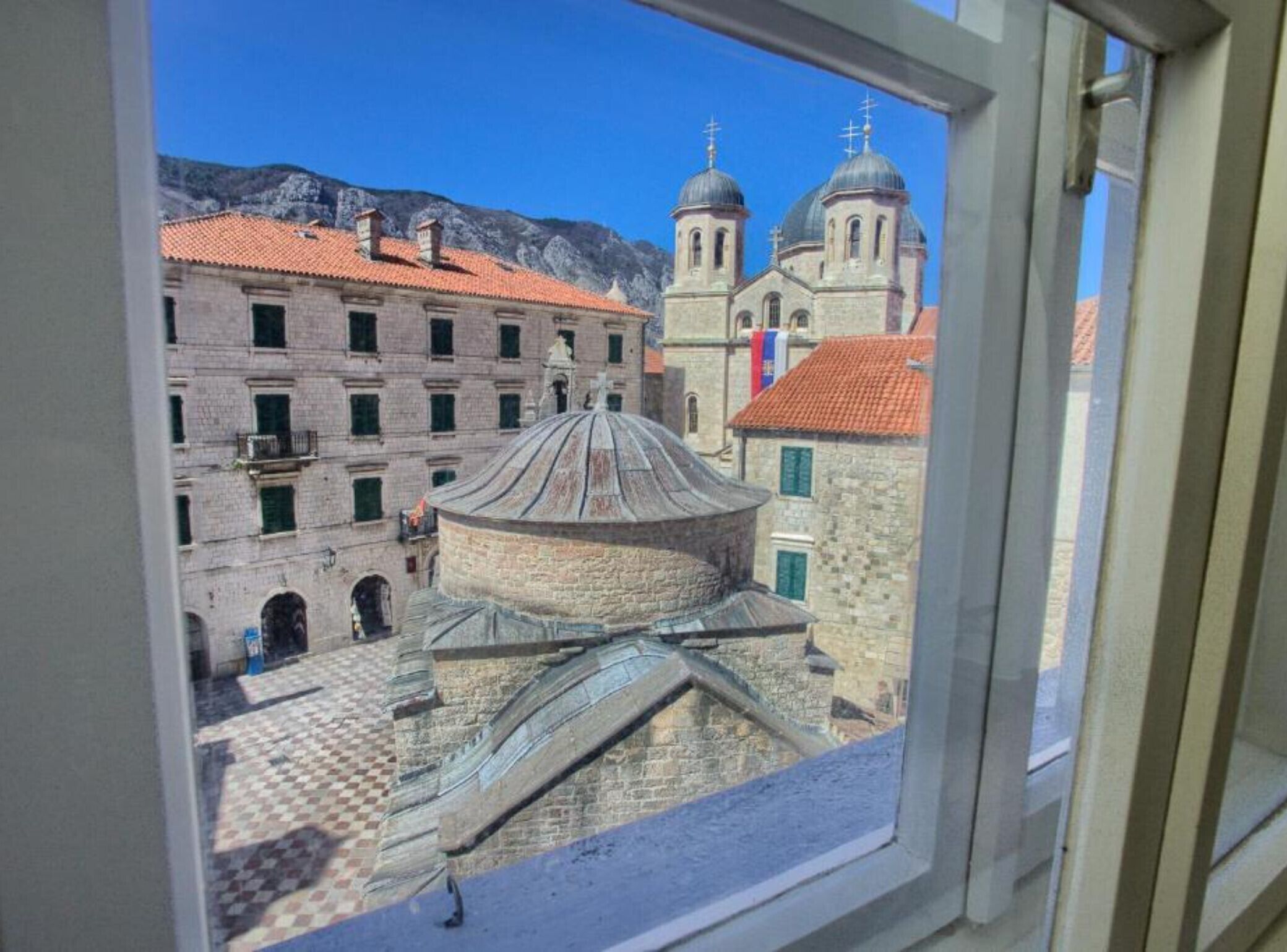 Une vue d’un bâtiment historique doté d’un dôme et d’un clocher, prise à travers une fenêtre.