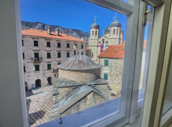 Vista de un edificio histórico con una cúpula y un campanario, a través de una ventana.
