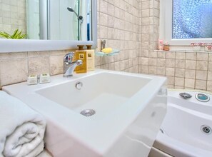A bathroom with a large white sink, a mirror, a shower, and a window with a view. - Kotor Old Town Charm Apartment - Two Bedroom Apt (Kotor)