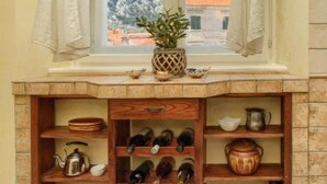 Una cocina con ventana, estantes con utensilios de cocina y vistas a un paisaje nevado.
