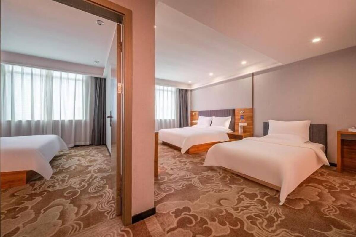 A hotel room with two beds, a large mirror, and a carpeted floor.
