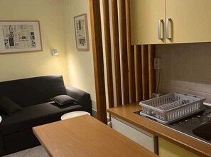 Cozy living space with a kitchenette, sofa, and dining table, perfect for travelers seeking a simple and functional stay.